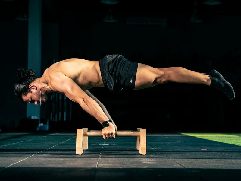 Man performing a controlled bodyweight exercise in a minimalist gym.